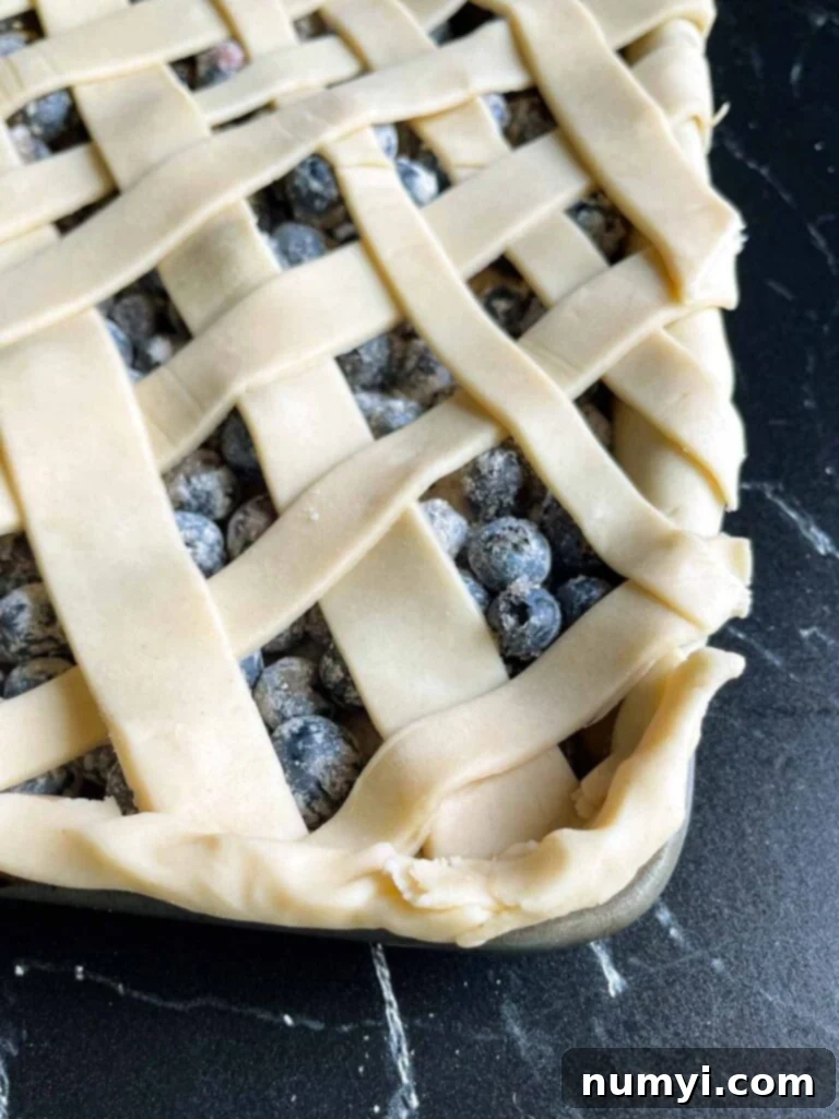 A close-up view of the intricate corner of a lattice crust on a blueberry slab pie, highlighting the crimped edges.