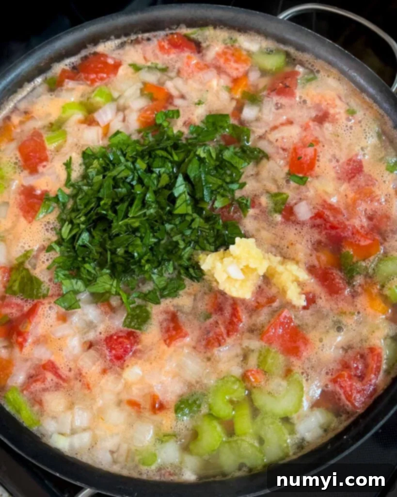 Pot of Sicilian chicken noodle soup simmering with the parsley and garlic added.