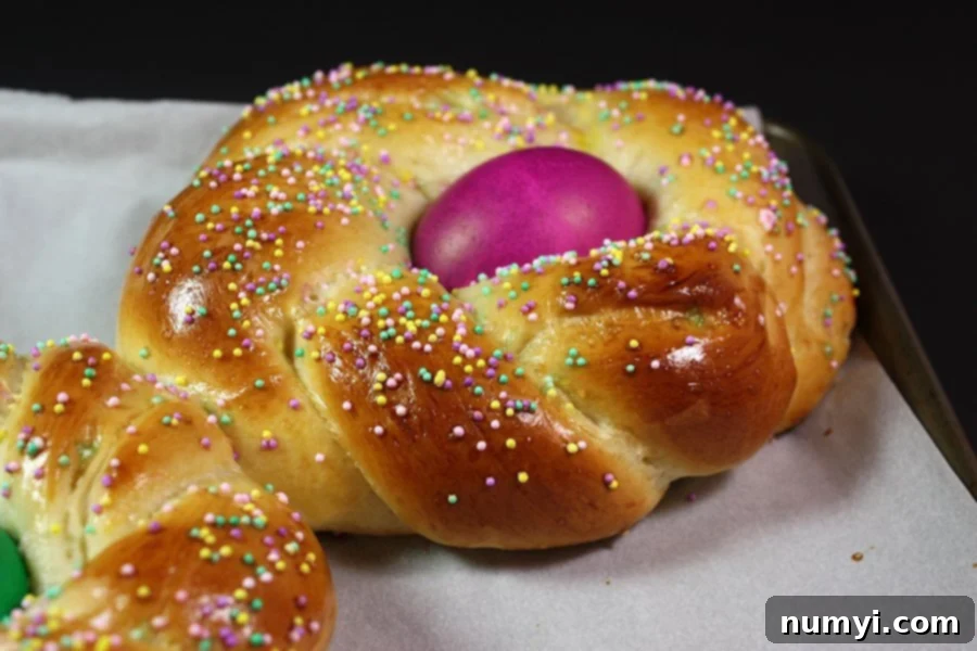 Sweet Italian Easter Loaf 2 Beautifully braided Italian Easter bread with colorful eggs on a baking sheet, ready for holiday festivities.