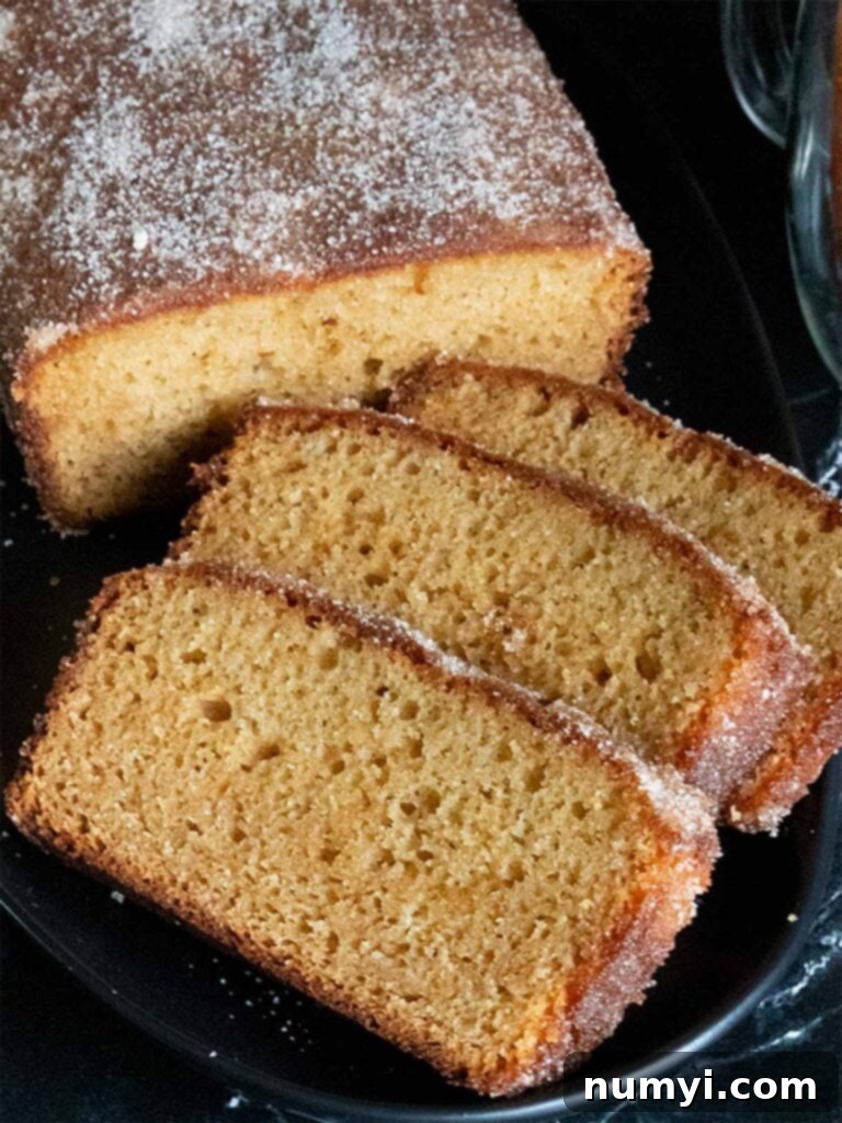 Apple cider doughnut loaf cake sliced on a black platter, showcasing its moist texture and cinnamon sugar topping.