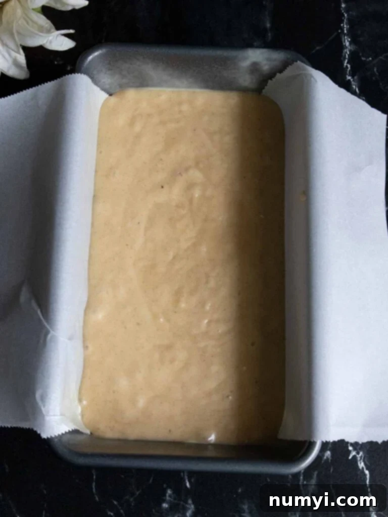Smooth cake batter poured into a parchment-lined loaf pan, ready for baking.