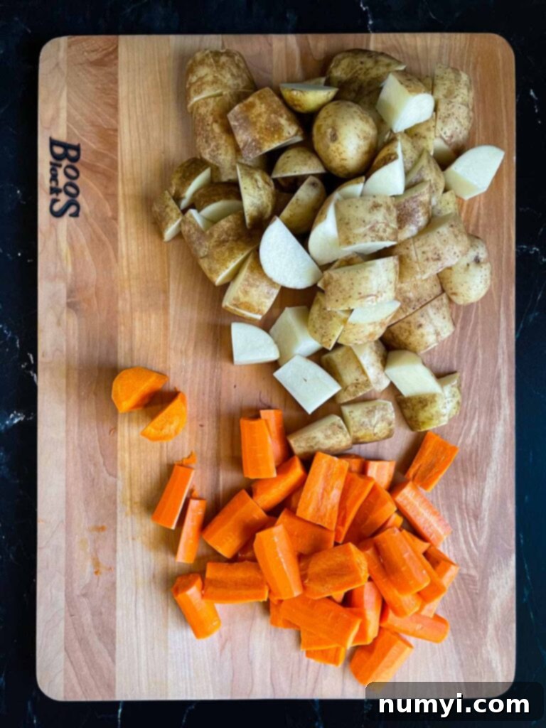 One-Pan Wonder: Roasted Chicken and Vegetables 4 Cut raw potatoes and carrots on a wooden cutting board.