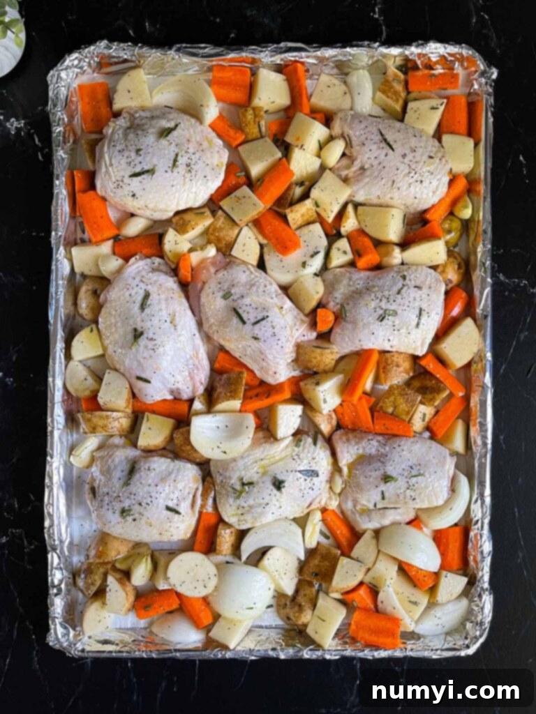 One-Pan Wonder: Roasted Chicken and Vegetables 6 Seasoned raw chicken and vegetables in a foil and parchment paper lined rimmed baking sheet.