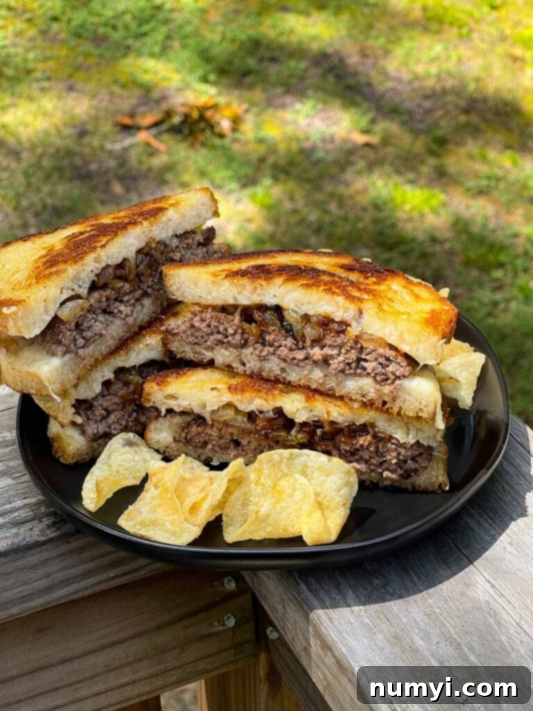 A delicious patty melt on a black plate, served with a side of chips.