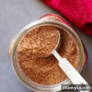 Top down of taco seasoning in a jar with a measuring spoon in it.