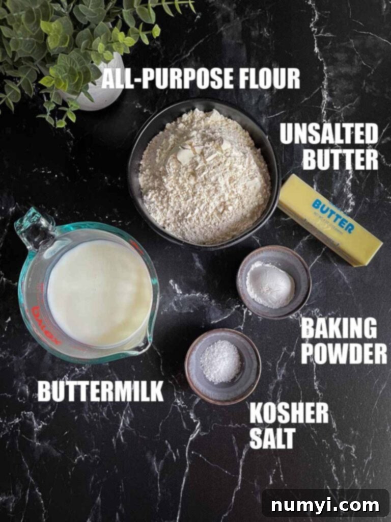 Effortless Butter Swim Biscuits 3 Essential ingredients for butter swim biscuits: all-purpose flour, unsalted butter, buttermilk, baking powder, granulated sugar, and kosher salt displayed neatly on a black marble countertop, ready for baking.