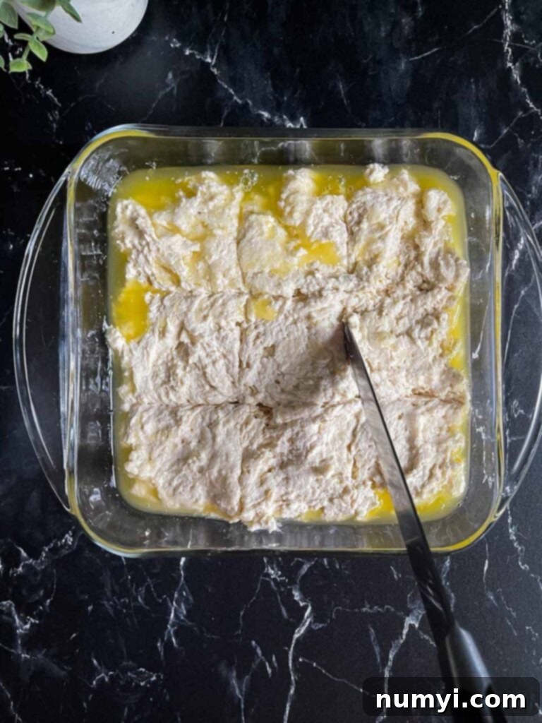 Effortless Butter Swim Biscuits 8 A sharp knife carefully scoring the biscuit dough into perfect squares directly in the butter-filled baking dish.