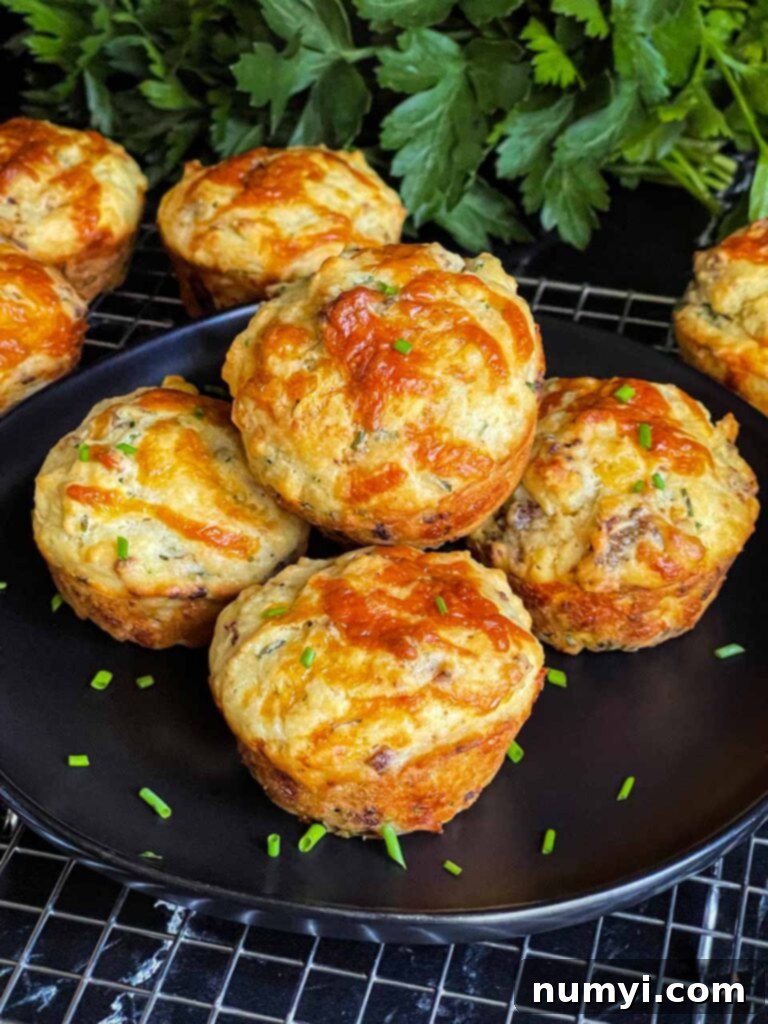 Sausage muffins stacked on a black plate garnished with diced chives.