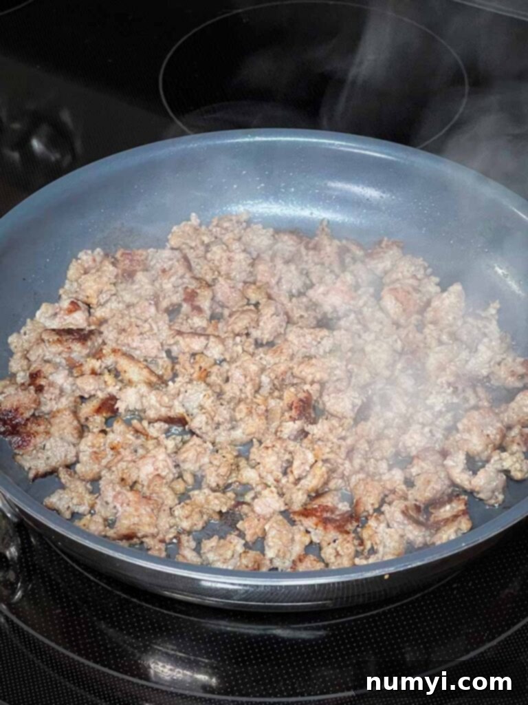 Breakfast sausage browning in a skillet.