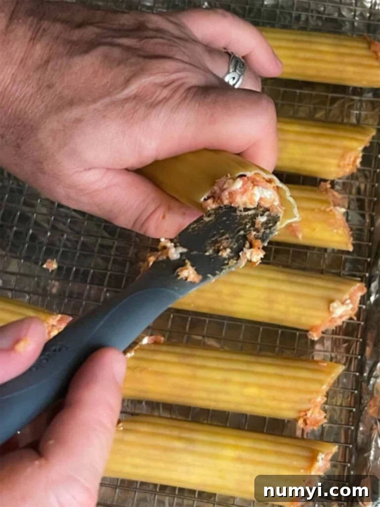 Stuffing the manicotti shells with the sausage mixture for smoked shotgun shells.