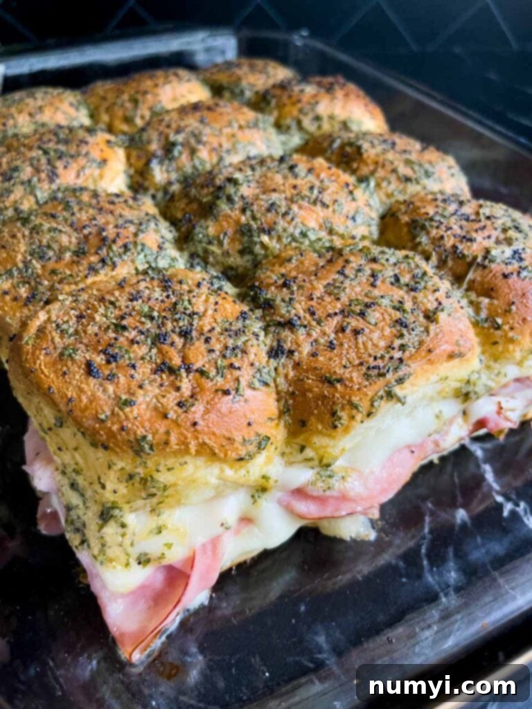 Baked ham and swiss cheese sliders fresh out of the oven, with golden brown tops and melted cheese visible.