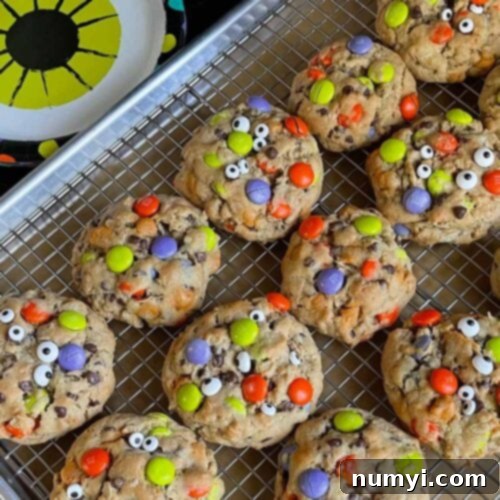 Halloween monster cookies on a wire rack in a baking sheet.