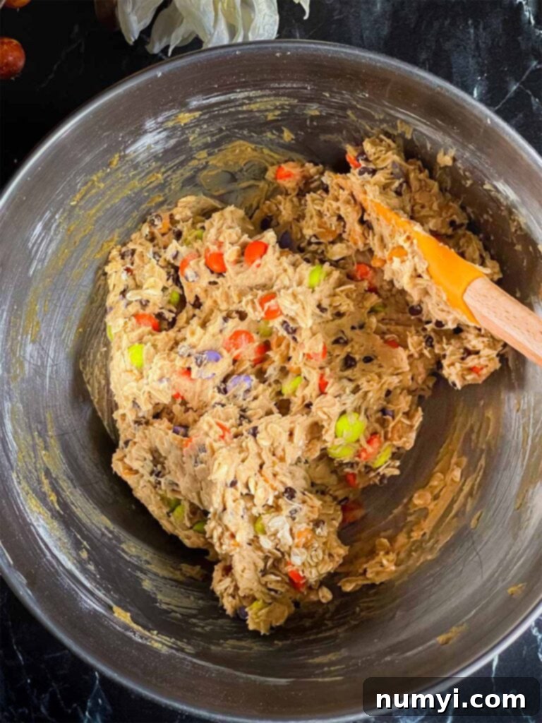 Halloween monster cookie dough in a metal mixing bowl, showcasing its texture and the mix-ins.