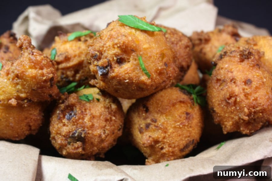 Freshly fried Jalapeno Hushpuppies stacked high in a rustic basket lined with brown paper, showcasing their golden-brown perfection and inviting texture.