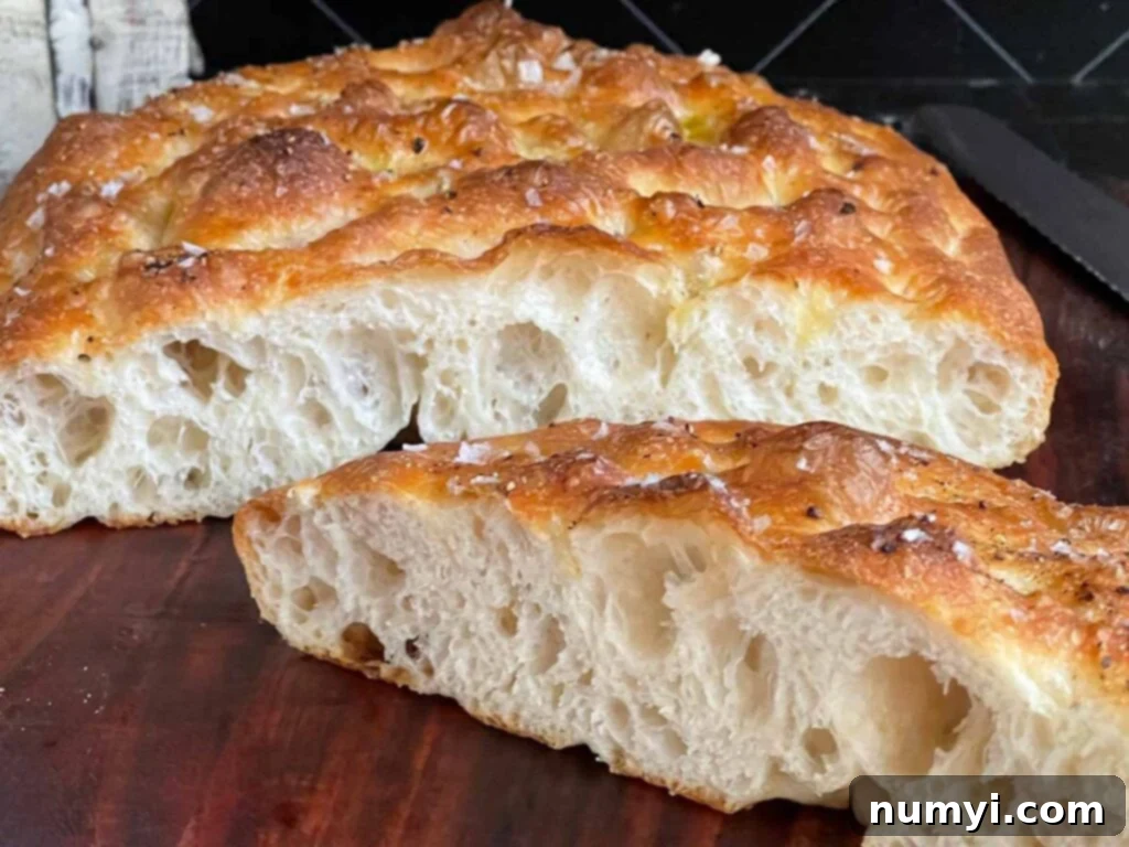 Focaccia bread cut in half on a wooden cutting board.