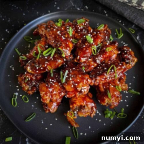 A plate of Asian chicken wings garnished with green onions and sesame seeds, highlighting their appetizing appearance.