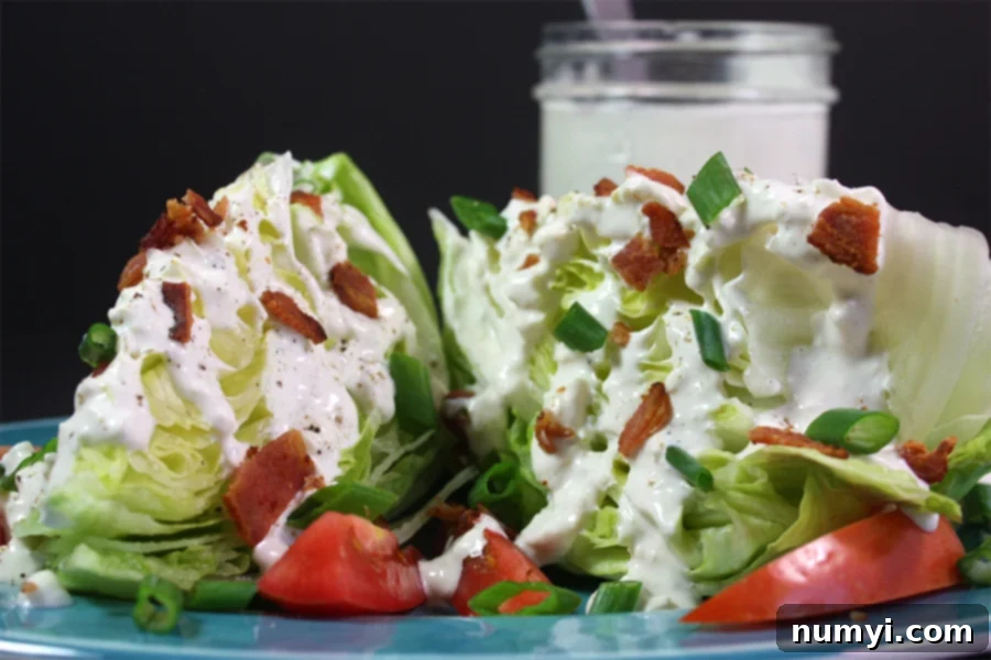 A vibrant blue cheese wedge salad served on a stylish blue plate, garnished with fresh tomatoes, crisp bacon, and a generous drizzle of creamy dressing.