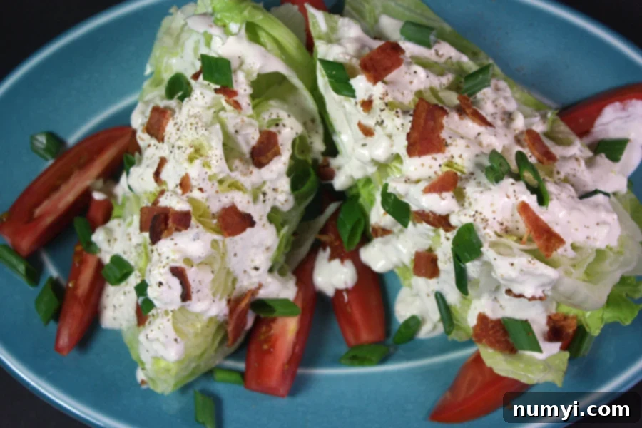 A perfectly assembled blue cheese wedge salad, showcasing the crisp lettuce, rich dressing, and colorful toppings.