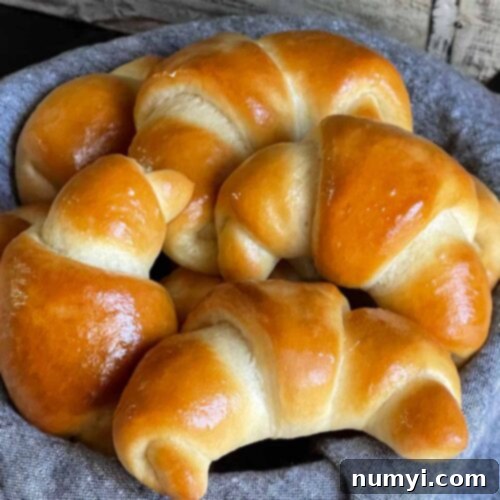 Crescent rolls in a bread basket lined with gray towel.