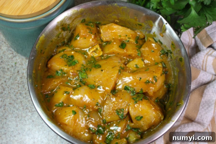 Golden Spice Chicken Skewers 4 Turmeric Chicken Kabobs - raw chicken pieces soaking in marinade in a glass bowl.