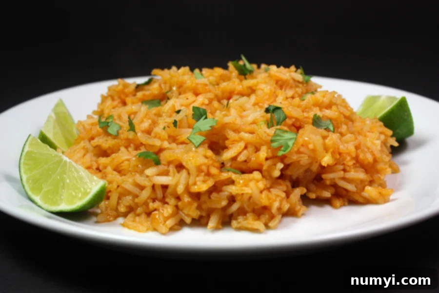Your Favorite Restaurant Style Mexican Rice At Home 6 Mexican Rice with a cilantro and lime garnish on a white plate.