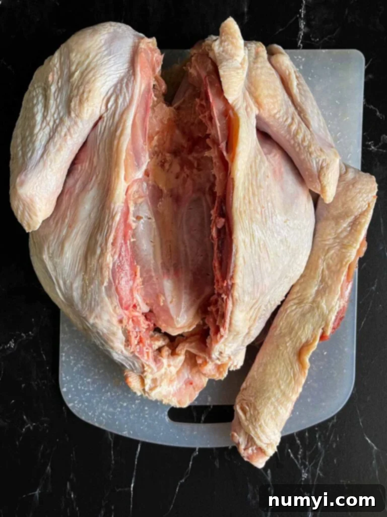 The Ultimate Dry Brined Spatchcock Turkey 8 A turkey with its backbone removed on a white cutting board.