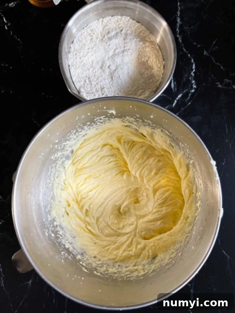 Cream butter and sugar for old fashioned sour cream pound cake in a metal mixing bowl with the dry ingredients in another metal bowl.
