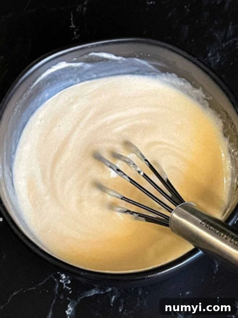 Broccoli salad dressing ingredients combined in a dark bowl.