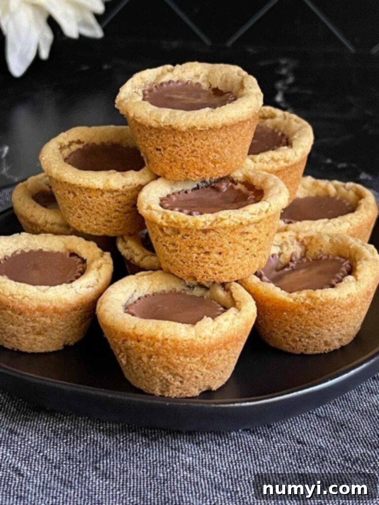Chocolate Peanut Butter Cup Cookies 8 A stack of perfectly baked peanut butter cup cookies on a dark plate, showcasing their inviting appearance.
