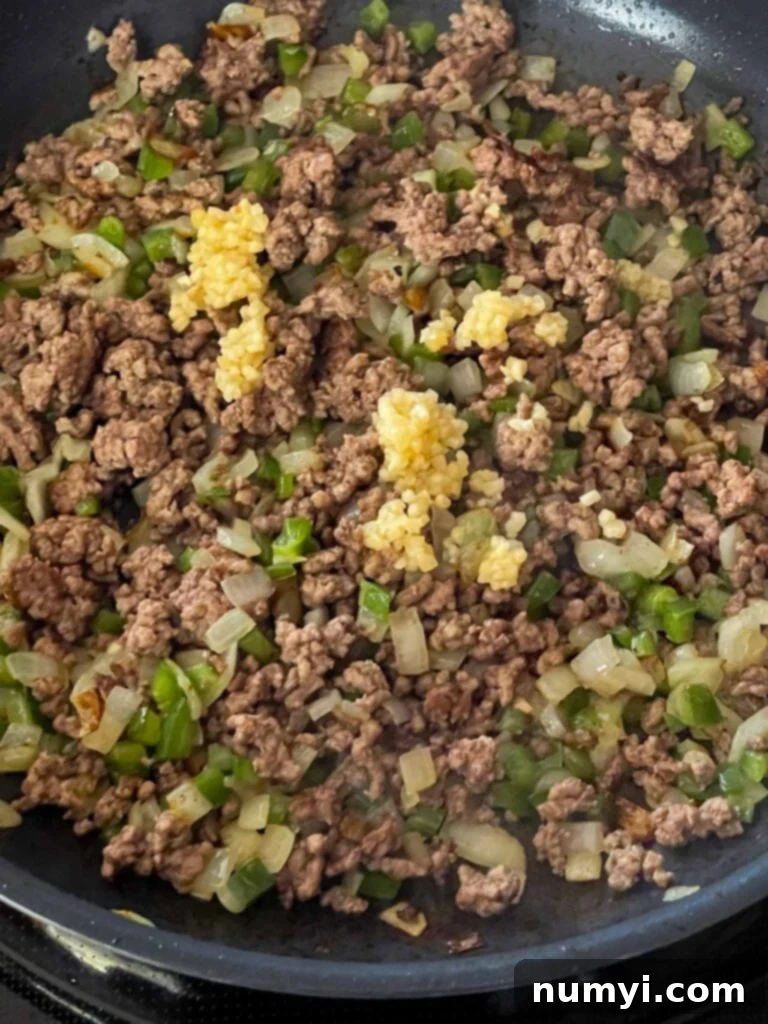 Molten Beef & Cheese Dip 6 Cooked ground beef mixed with sautéed onions, garlic, and jalapeños in a skillet, ready for the next step.