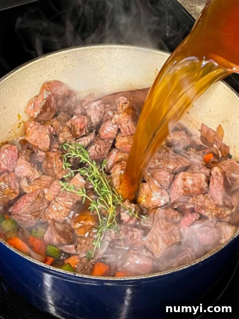 Beef broth being added to the beef barley soup.