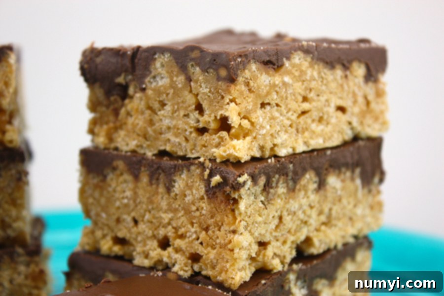 Close-up of perfectly cut Scotcharoos stacked neatly on a vibrant blue plate, showcasing their glossy chocolate and butterscotch topping.