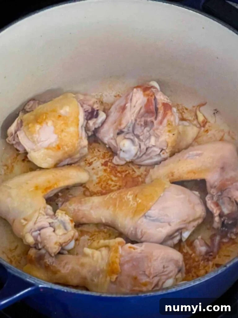 Chicken being browned in a dutch oven.