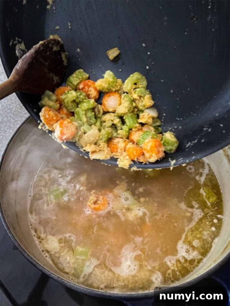 Cooked vegetable roux being added to chicken stock.