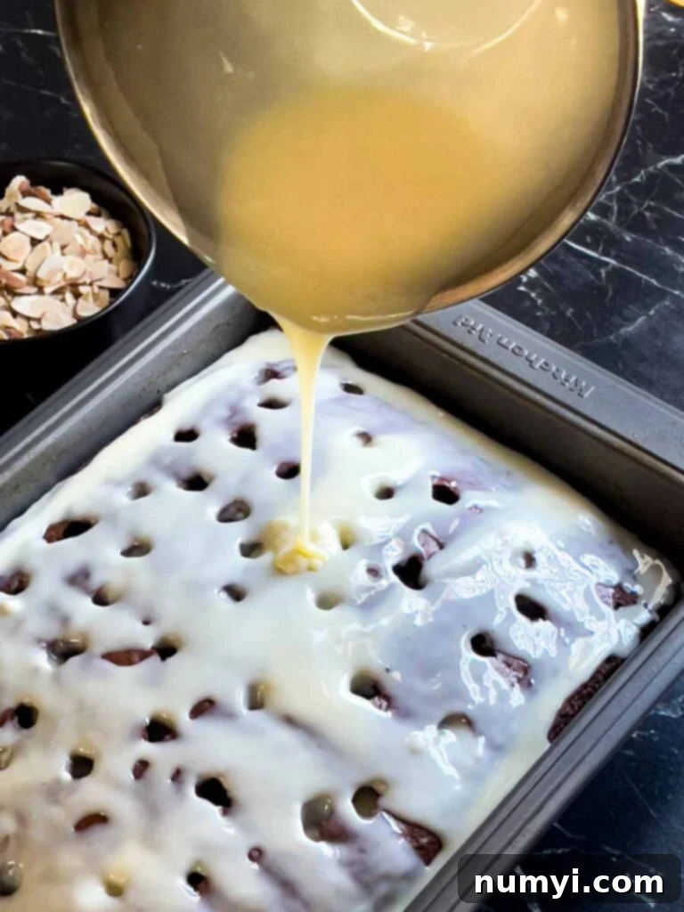 The milk mixture being poured over the Almond Joy cake with holes poked into it.