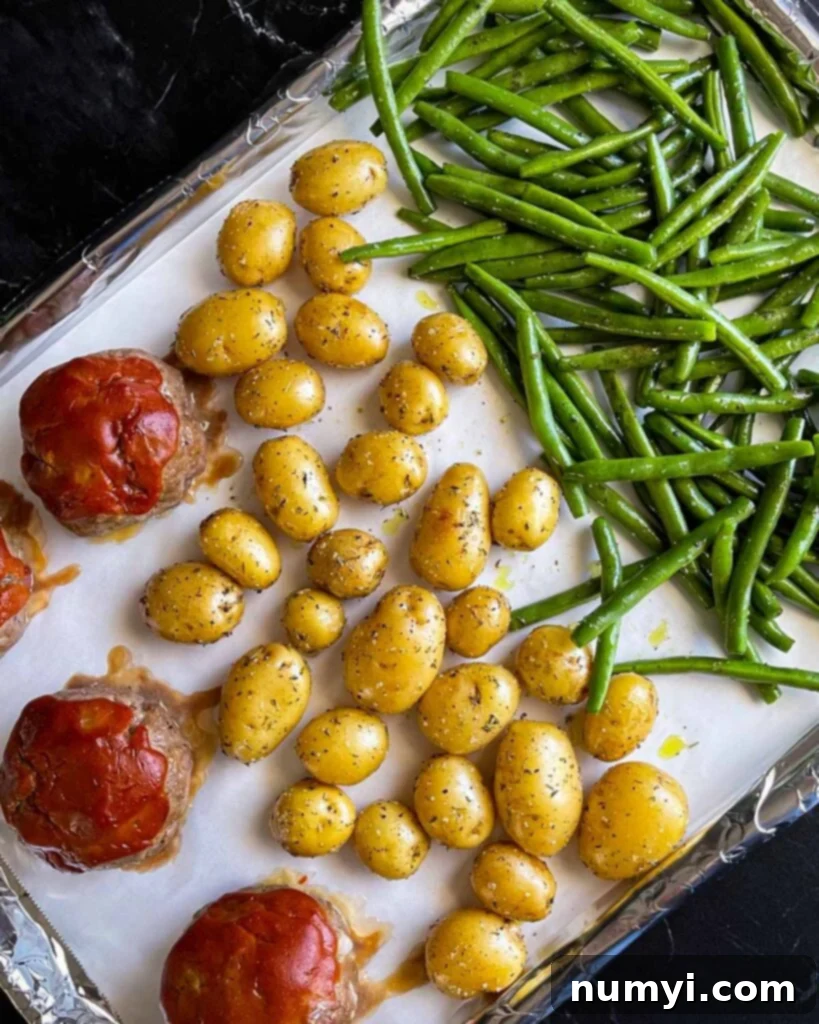 The green beans added to the baking sheet with the mini meatloaves and potatoes.