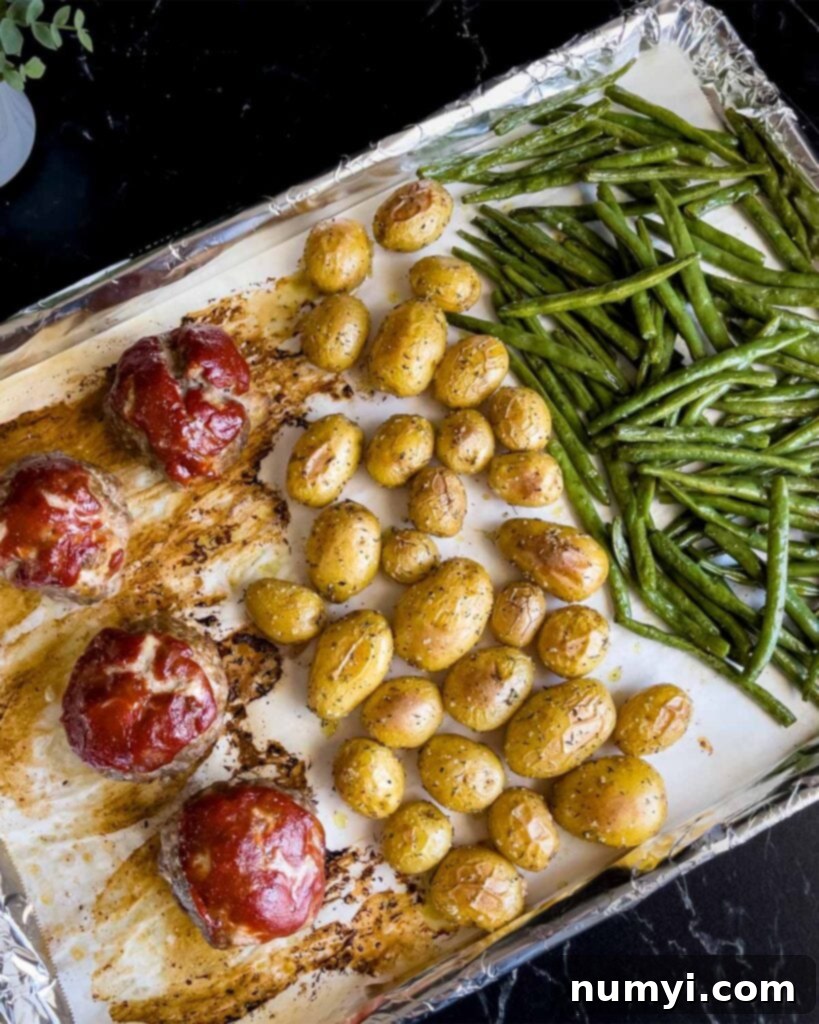 Sheet pan mini meatloaves with green beans and potatoes after cooking.