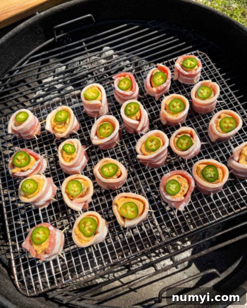 Smoked Bacon Sausage Bites 12 Smoked pig shots cooking on a Weber grill set up for indirect heat, surrounded by wood smoke.