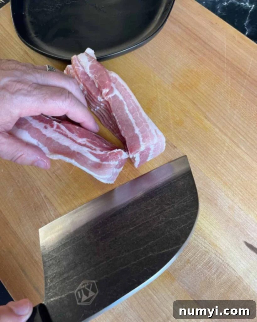Smoked Bacon Sausage Bites 6 Thick-cut bacon strips being sliced in half lengthwise on a cutting board for pig shots.