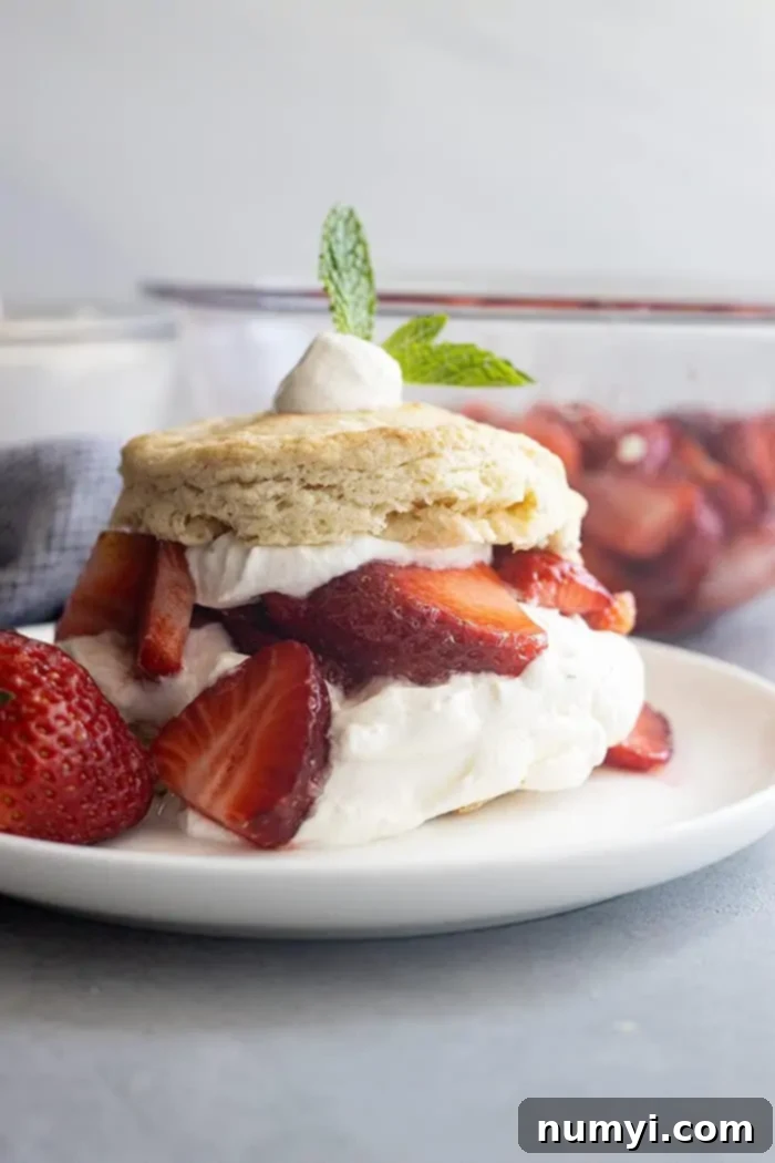 Delicious Strawberry Shortcake on a white plate, showcasing juicy, ripe strawberries and a generous dollop of freshly whipped cream on a golden biscuit.