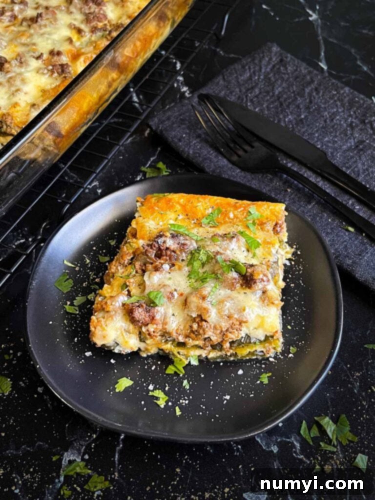 The Ultimate Chile Relleno Casserole 14 A serving of chile relleno casserole on a dark plate with the casserole in the background.