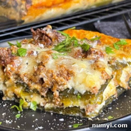 The Ultimate Chile Relleno Casserole 15 A serving of chile relleno casserole on a dark plate with the casserole in the background.
