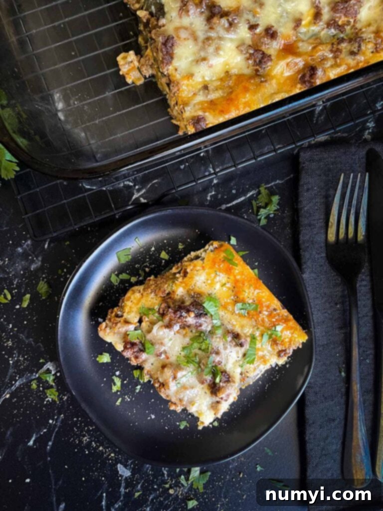 The Ultimate Chile Relleno Casserole 3 A serving of chile relleno casserole on a dark plate with the casserole in the background.