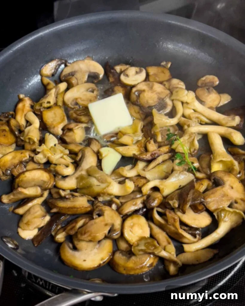 Velvety Mushroom Risotto 13 Sautéed mushrooms in a skillet with butter, fresh thyme sprigs, and a crushed garlic clove added.