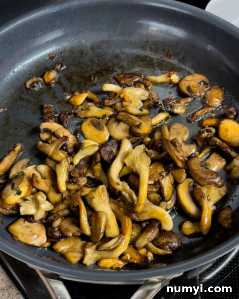 Velvety Mushroom Risotto 14 Rendered down and caramelized mushrooms in a skillet, appearing glossy from butter.