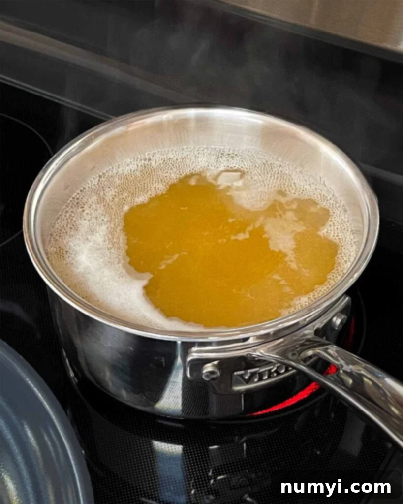 Velvety Mushroom Risotto 5 A saucepan on a stovetop with chicken stock gently simmering.