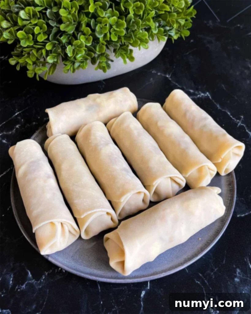 Uncooked redneck eggrolls on a dark plate.