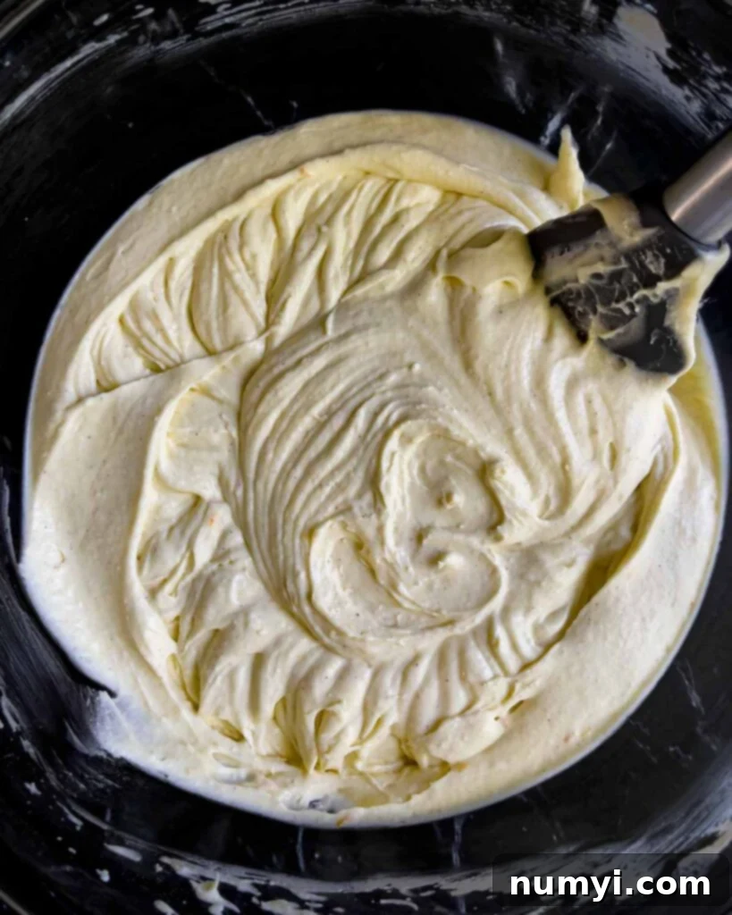 The fully mixed, smooth, and creamy cannoli cheesecake batter in a glass bowl, ready for chocolate chips.