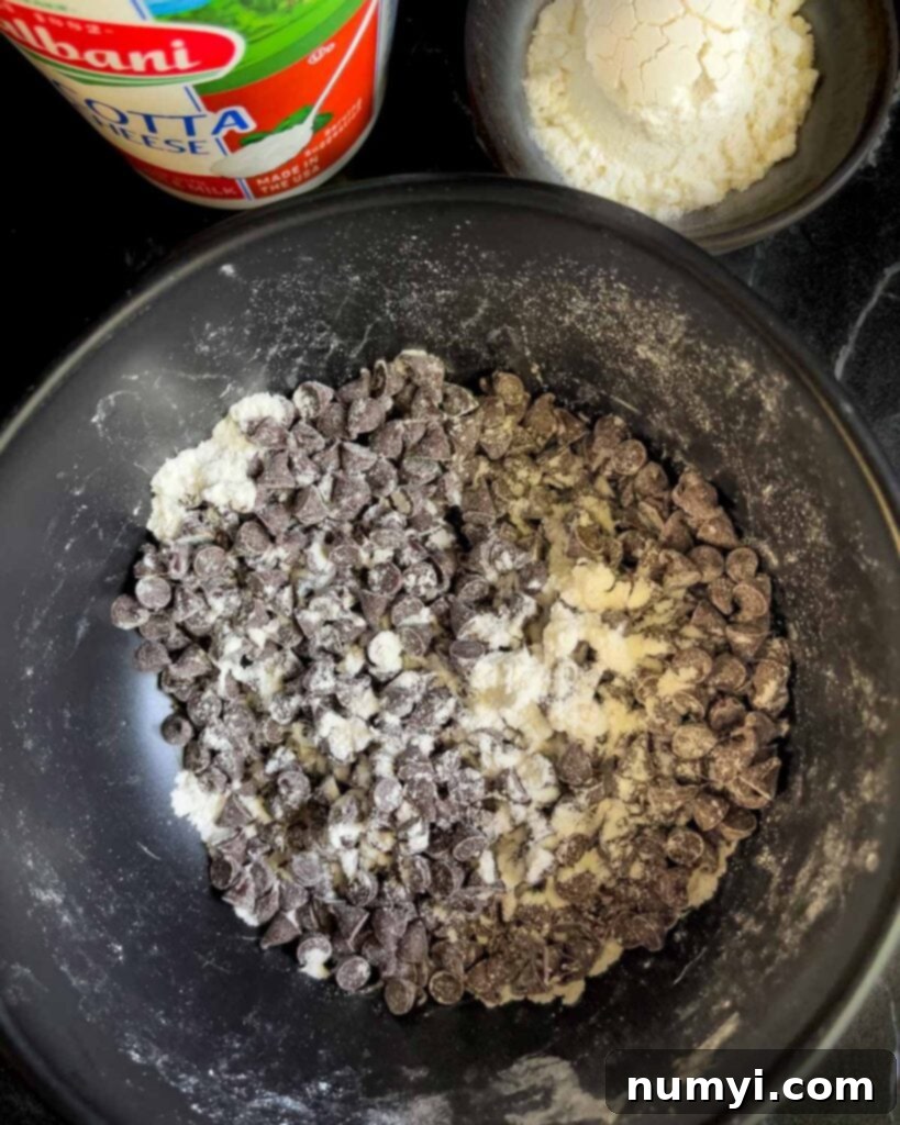 Mini chocolate chips lightly tossed with a small amount of flour in a bowl, preparing them for even distribution.
