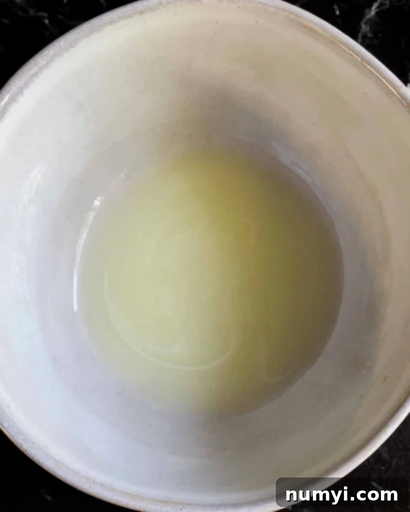The significant amount of liquid (whey) collected in the bottom bowl after draining the ricotta cheese overnight.